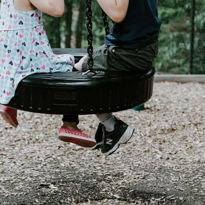 Ein Junge und ein Mädchen sitzen in einer Reifenschaukel.