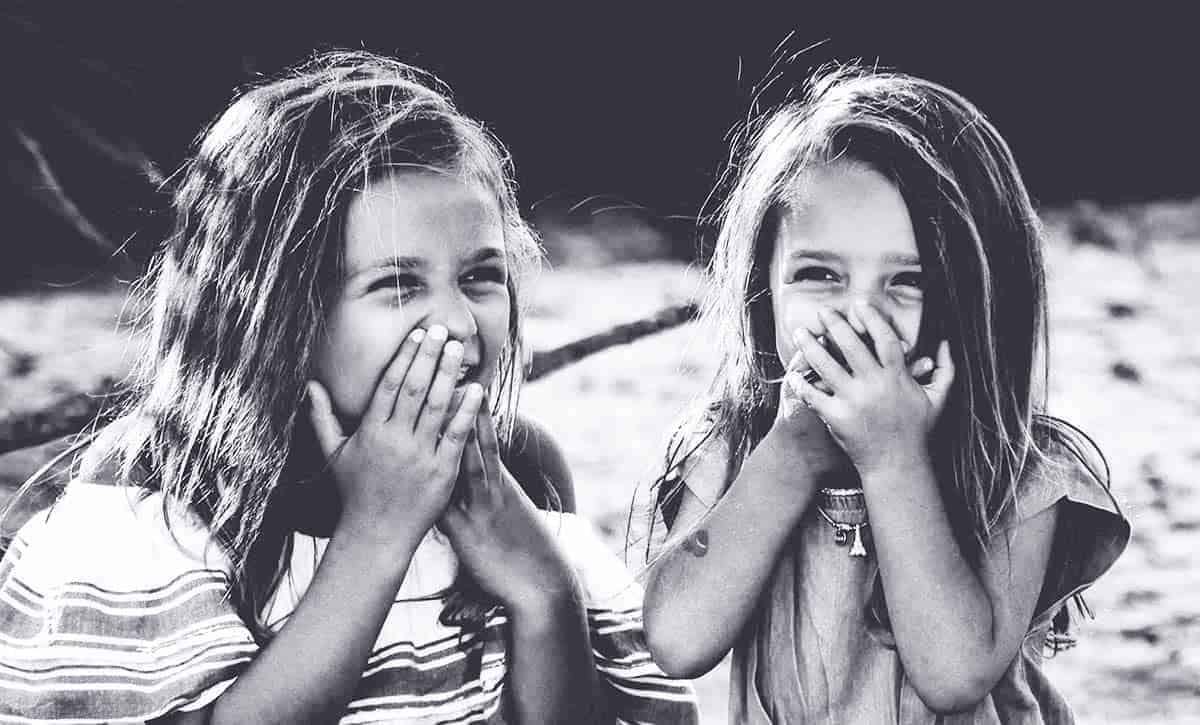 zwei Mädchen lachen und halten sich die Hände vor den Mund
