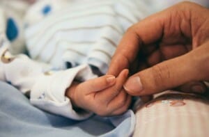 Eine große Hand hält die Hand eines Babys.