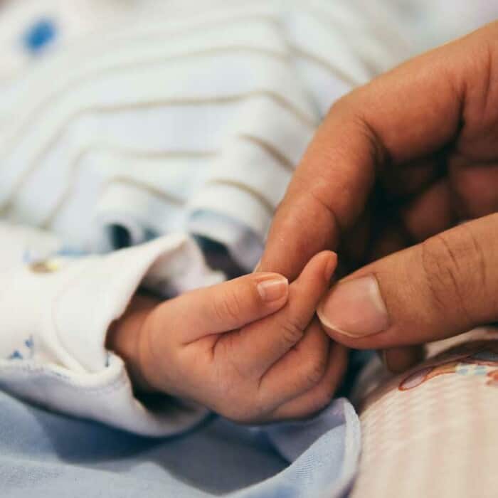 Eine große Hand hält die Hand eines Babys.