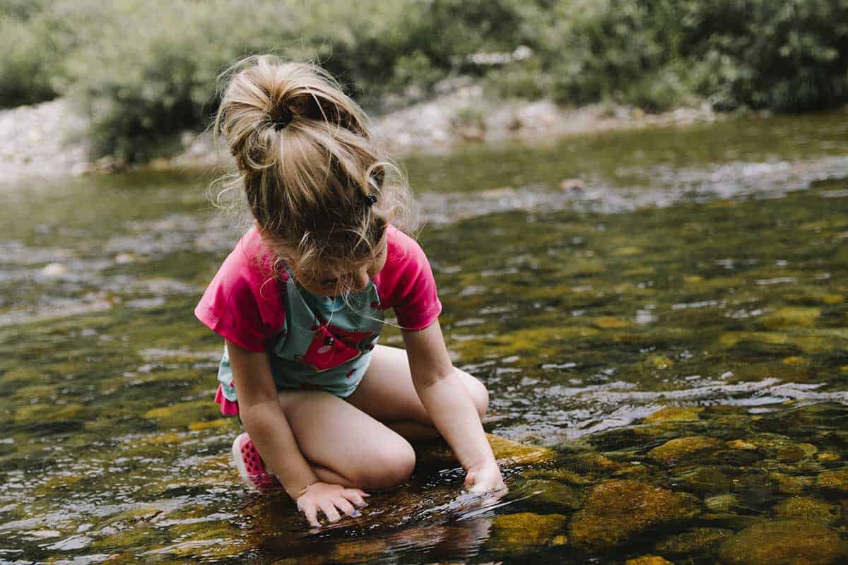 ein Kind kniet in einem Fluss