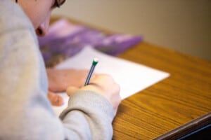Ein Junge schreibt mit Bleistift auf ein Papier