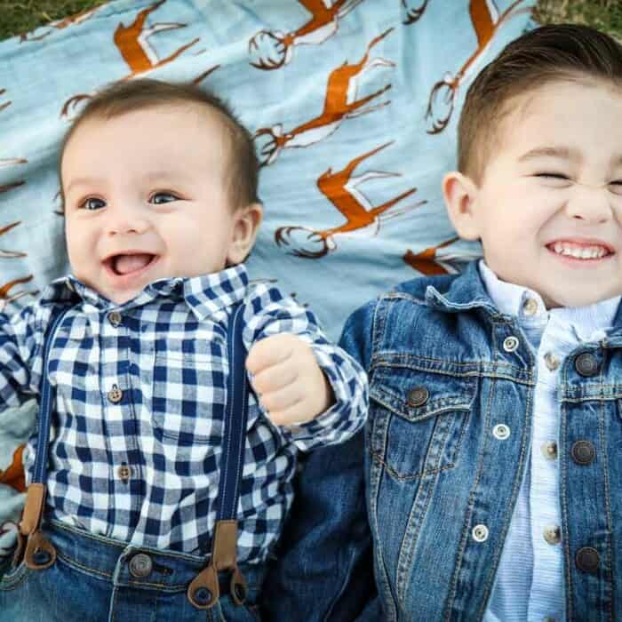 Zwei Jungen liegen lachend auf einer Decke.