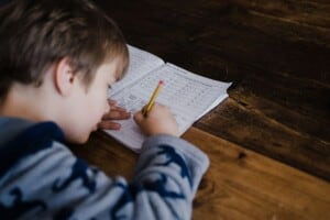 Ein Junge löst Aufgaben in einem Heft.