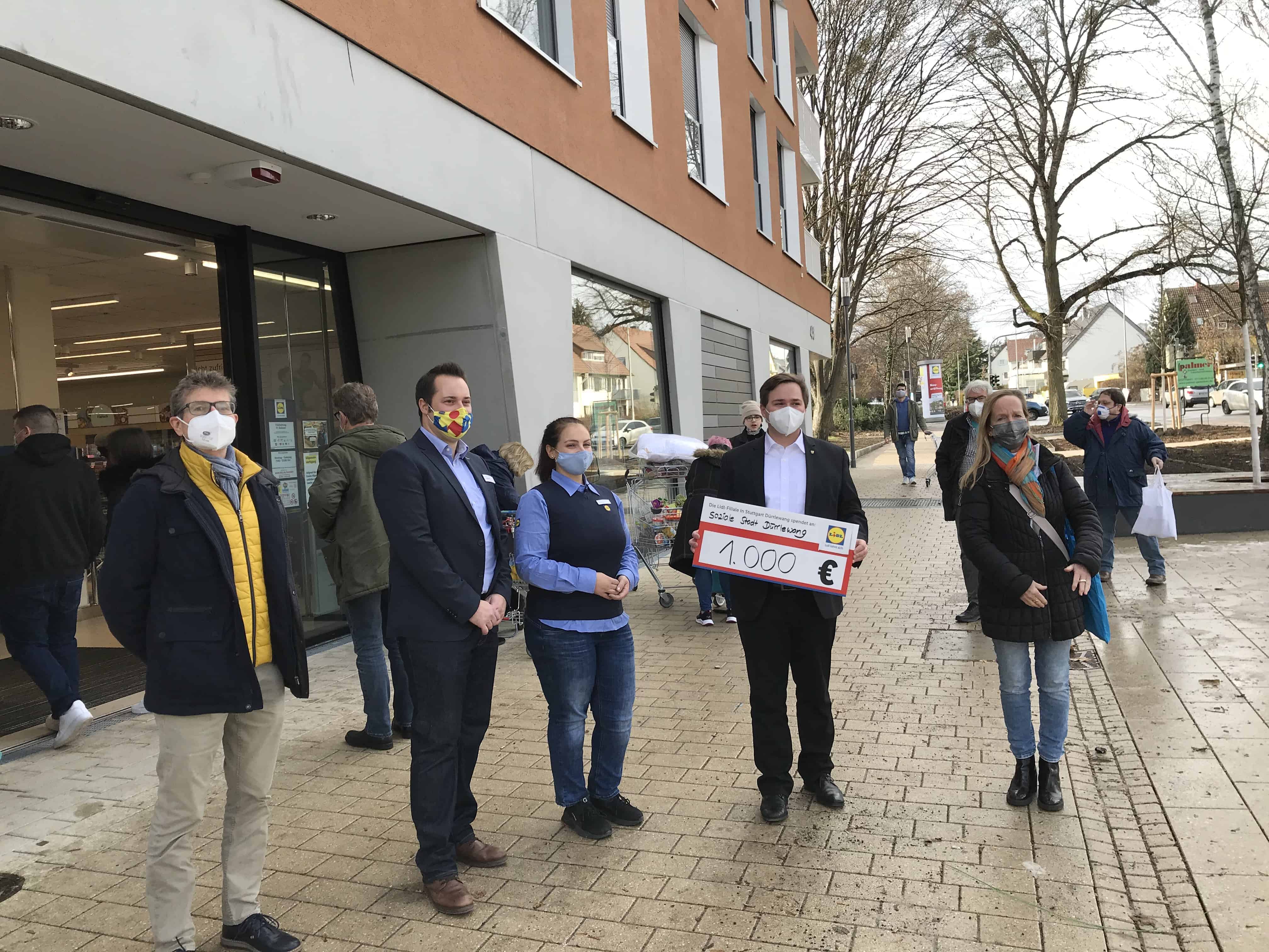 Vor einer Lidl-Filiale stehen drei Männer und zwei Frauen. EIner der Männer hält ein Schild in den Händen, auf dem steht: Soziale Stadt Dürrlewang, 1000€.