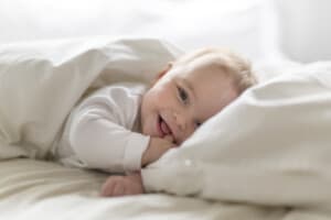 Ein Baby liegt in einem Bett und lächelt.