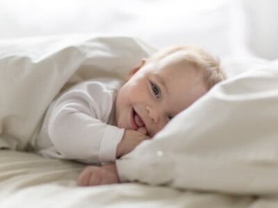 Ein Baby liegt in einem Bett und lächelt.