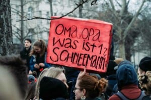 Ein rotes Schild ragt aus einer Demonstration heraus, auf dem steht "Oma, Opa, was ist ein Schneemann?"