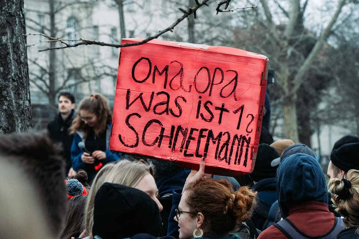 Ein rotes Schild ragt aus einer Demonstration heraus, auf dem steht "Oma, Opa, was ist ein Schneemann?"