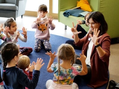 Kinder lernen mit einer Erzieherin zählen mit den Händen.