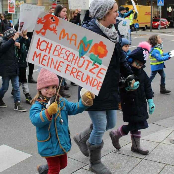 Kinder und Erwachsene in Winterkleidung demonstrieren auf der Straße mit Schildern für Kinderrechte.