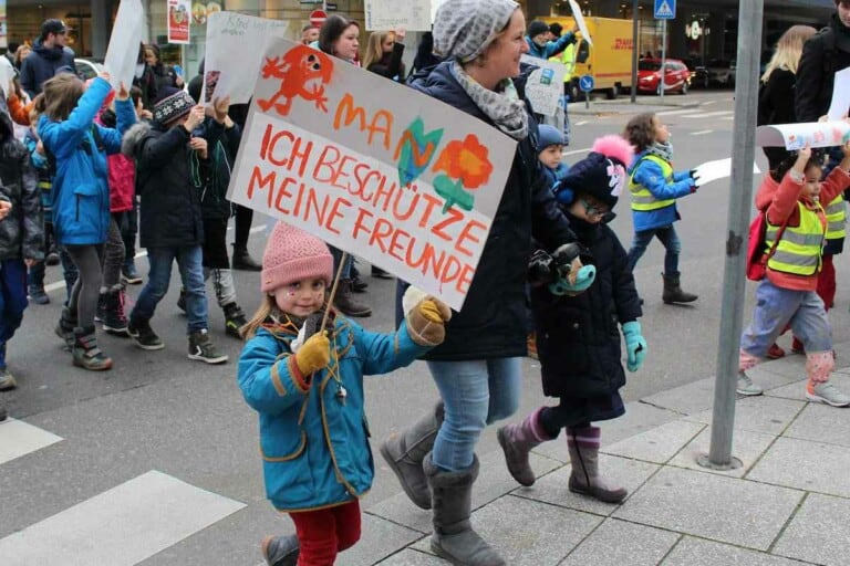 Kinder und Erwachsene in Winterkleidung demonstrieren auf der Straße mit Schildern für Kinderrechte.