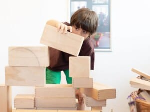 Ein Junge stapelt konzentriert Holzklötze aufeinander.