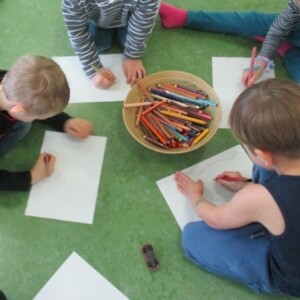 Eine Gruppe Kinder sitzt auf dem Boden und malt.