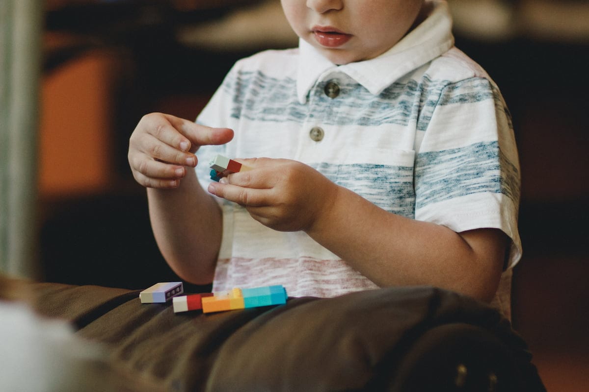 Ein Kind baut mit verschiedenfarbigen Legosteinen.