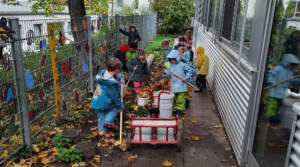 Kinder des Kinderhauses Knax-Garten helfen dabei, die Blätter im Garten zu entfernen.