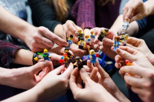 Verschiedenste Legofiguren werden von mehreren Händen gehalten.
