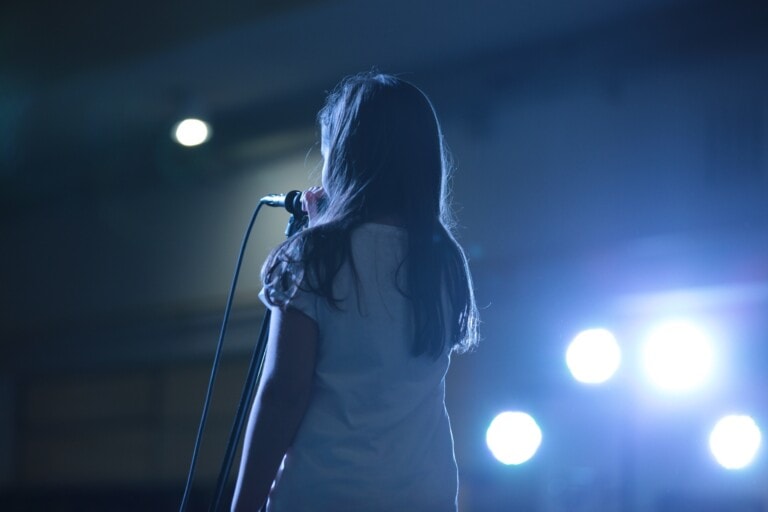 Mädchen spricht oder singt in ein Mikrofon auf der Bühne