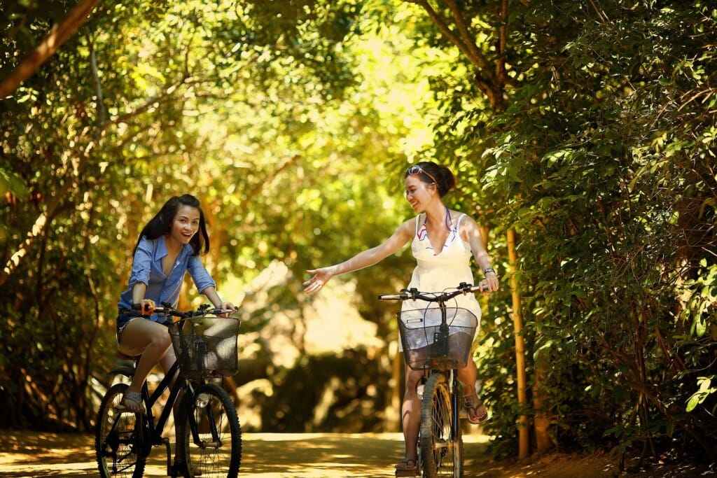 Zwei Mädchen, die in einem Wald Fahrrad fahren.