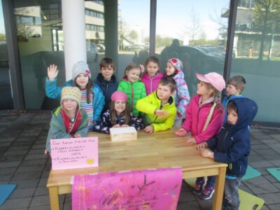 Eine Gruppe von Kindern steht hinter dem Verkaufstisch im Freien.