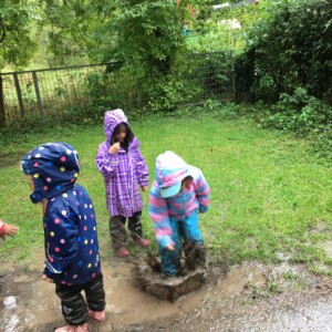 Drei Kinder spielen draußen im Matsch.