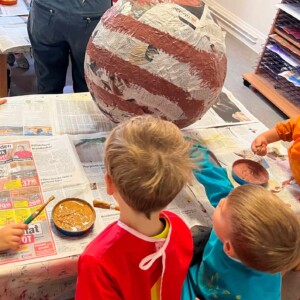 Kinder bemalen einen Pappmaché Planeten