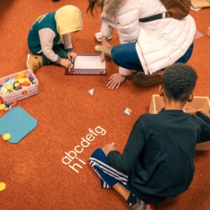 Kinder spielen auf einem orangenen Teppichboden