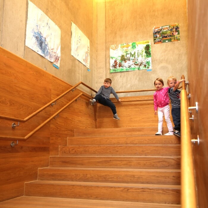 Kita-Kinder schauen von oben eine Treppe hinunter.